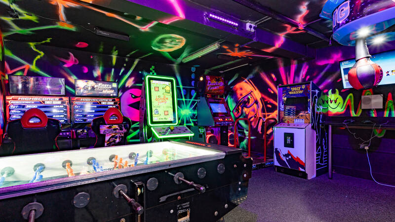 The arcade: racing simulators, a dance machine and cabinets under neon murals